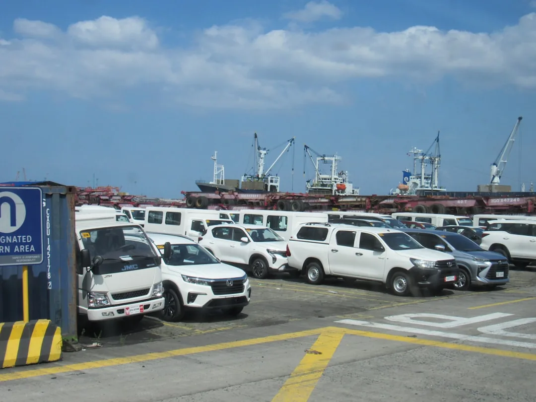 Used Korean export cars parked near cargo ships at a port
