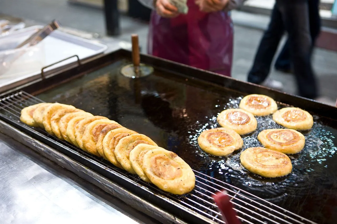 Hotteok, a syrup-filled Korean street food pancake, frying on a griddle