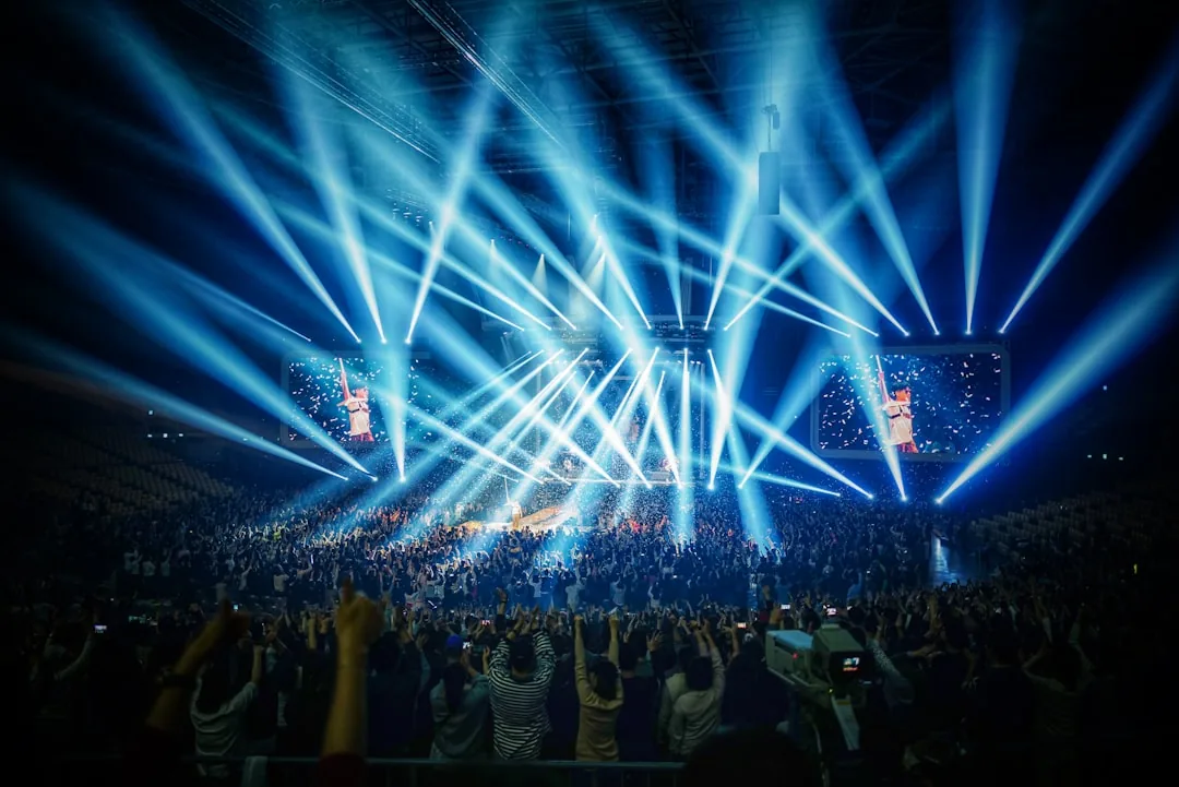 K-pop group performing on stage under blue concert lights